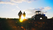 Silhouette couple walking through rural suburban area of field. Economic production with help of tractor machinery. Beautiful landscape nature. Suburban area with farm land. Healthy natural products.