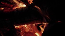Red hot fire, flames and coals and burning embers burning wood and logs in camp fire in cinematic slow motion.