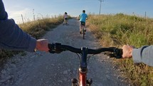 POV of two kids enjoying a bicycle ride on the countryside with their father.