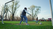 Parents teaches son how to play football. Happy family playing football outdoors. Boy playing soccer ball in the park.