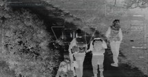 Military drone night vision thermal view of terrorists walking through a forest