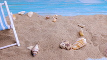 Sun lounger and seashells on the sand on a blue background. Summer vacation, beach, relaxation, sea, ocean, travel concept. Dolly shot