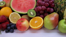 Assorted fresh fruits for healthy eating. Watermelon, pineapple, apple, pear, strawberry, kiwi, lemon, orange, grape, blueberry, pomegranate, mango, banana. Dolly shot 