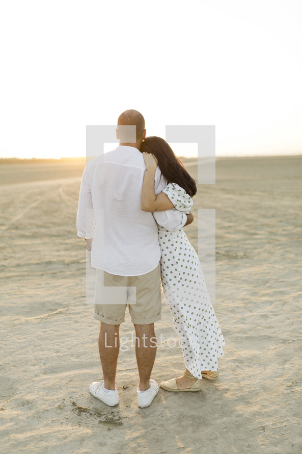 couple hugging outdoors with backs to the camera 