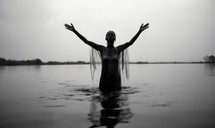 Baptism. Black and white portrait of a young black woman standing in the water in worship