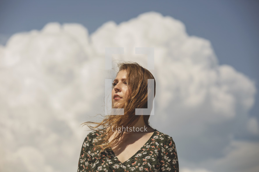 young woman alone in front of huge cloud bank