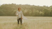 carefree woman walking through a field 