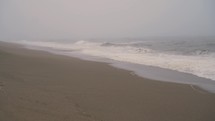 tide washing onto a foggy beach 