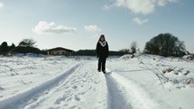 woman walking alone in a snowy road 