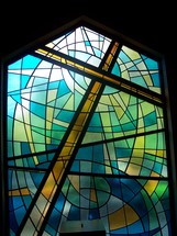 The power of the cross - Stained glass window art of the cross of Christ in shades of blue, green, gold and yellow showing the redeeming power of the Cross where Jesus was crucified and slain for the sins of mankind.