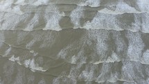 Aerial view of crispy waves breaking on the cliffs along the coast. Aerial view of tranquil foam waves breaking rocky cliff in a daytime