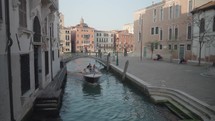 The atmosphere of narrow canals in the city of Venice, with many bridges and small boats parked.