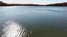 Drone footage of a serene lake surrounded by trees in the background. It captures the beauty of nature, highlighting elements such as the sky, landscape, and the various characteristics of a body of water. 