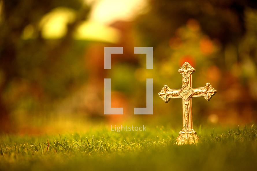 a gold cross in grass 