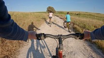 POV of two kids enjoying a bicycle ride on the countryside with their father