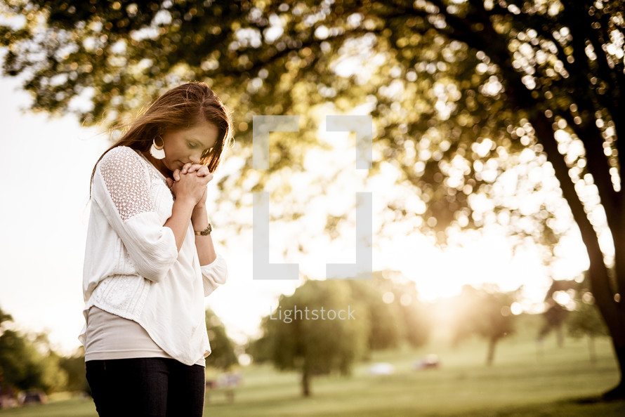 woman praying under a tree