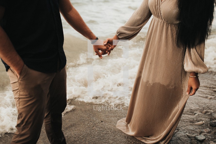 a couple holding hands standing in water 