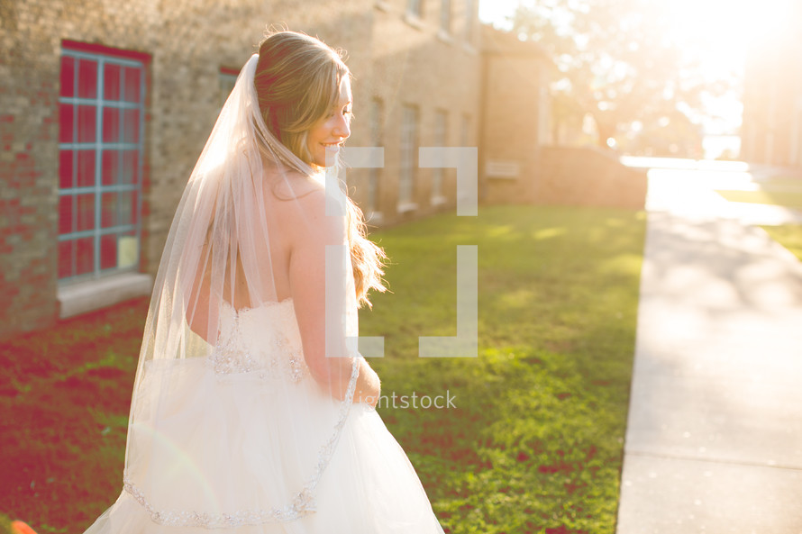 a bride walking outdoors under bright sunlight 