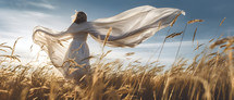 A woman in a white gown walking in a wheat field.