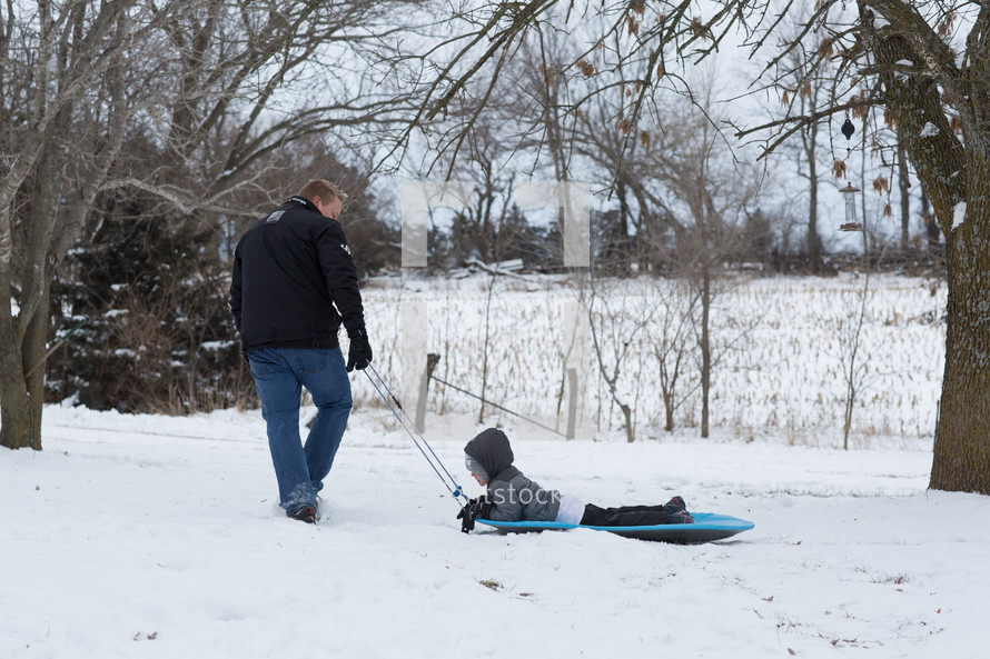 father and son sledding in the snow 