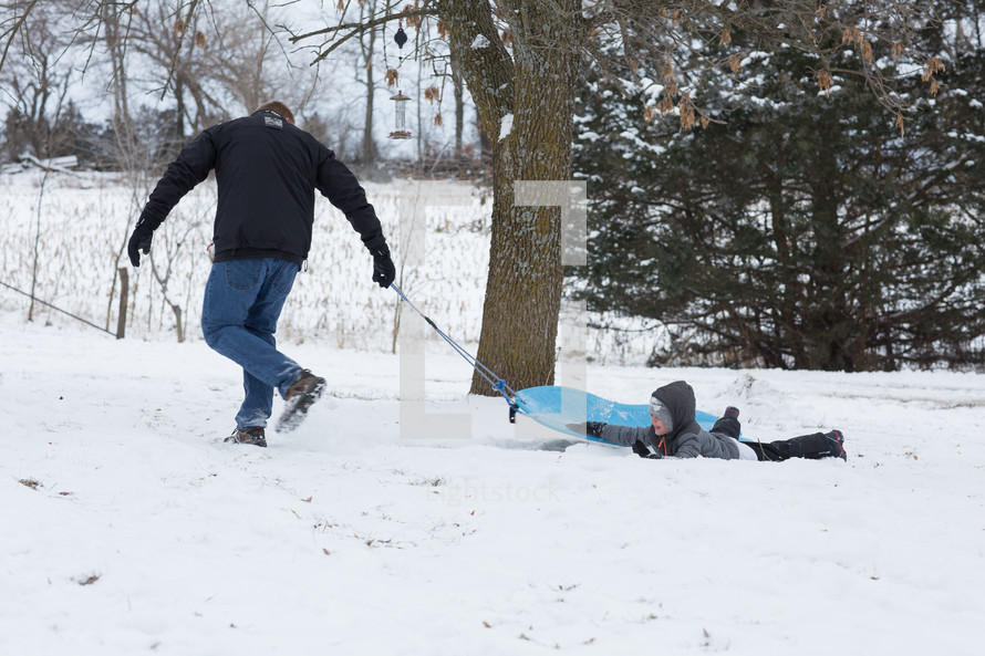 father and sons sledding in the snow 