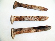 A set of three old, rusty and weather torn steel nails like the ones used to crucify Jesus and nail His hands and feet to the cross. 