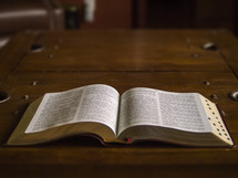 Bible laying open on a wooden table.