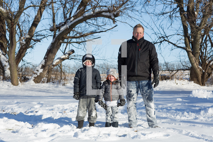 portrait of a father and his sons standing in the snow 