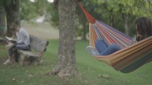 Young woman reads her Bible in a hammock between two trees