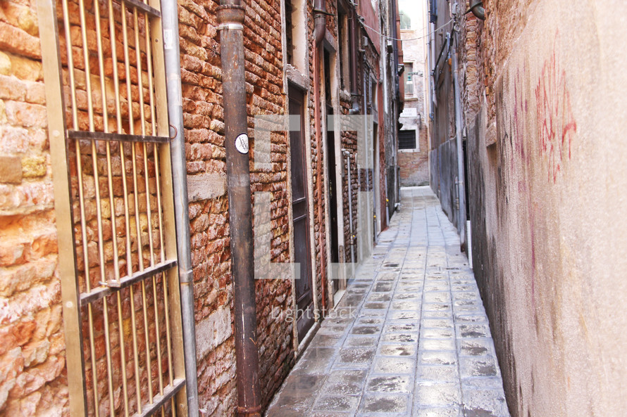 Narrow passage with pipes and bars, a back street of Venice