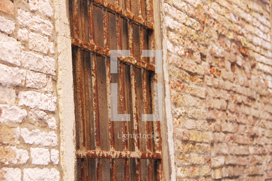 Window with rusting bars and ancient bricks