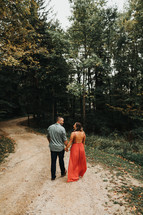 couple walking holding hands on a dirt road 