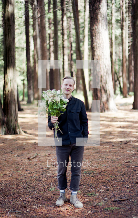 a man in a forest with a bouquet of flowers 