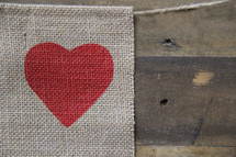 heart on a burlap banner over a wooden background