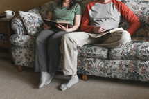a couple sitting on a couch watching church online