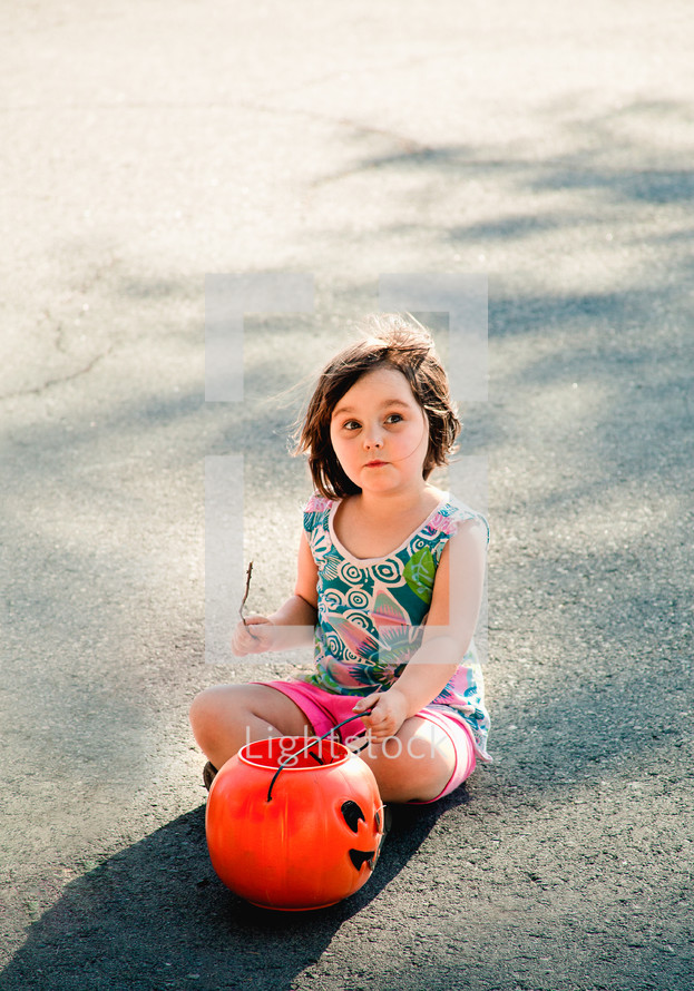 a girl child holding a jack-o-lantern 
