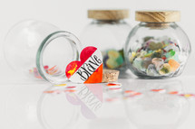 Jars of paper hearts on a white background with one lettered BRAVE in front.