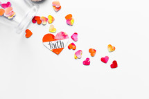 Top view of watercolor hearts scattered on white background with one labeled FAITH. 
