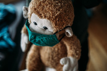 toddler hugging a stuffed animal monkey wearing a face mask 