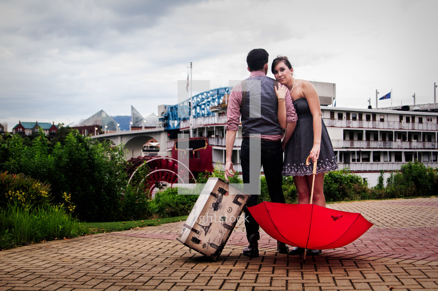 a couple with a trunk and red umbrella 