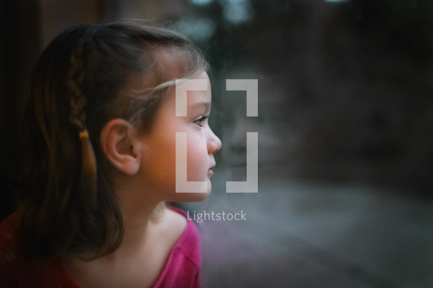a little girl looking out a window 