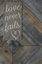 love never fails on wooden background