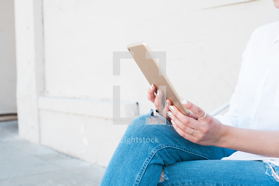 a woman sitting looking at an iPad 