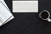 coffee mug, computer keyboard, Bible, and journal on a desk 