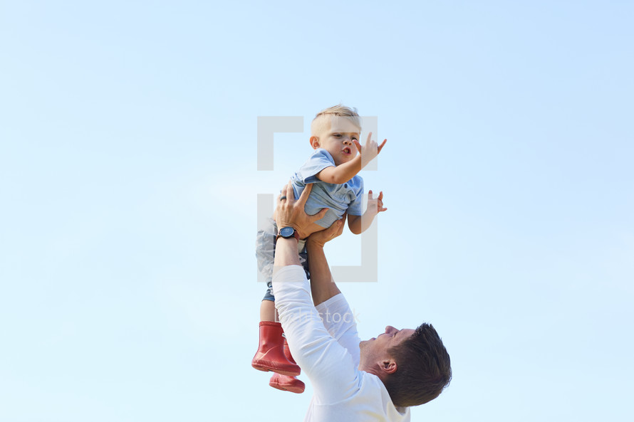 a man holding his son up outdoors 