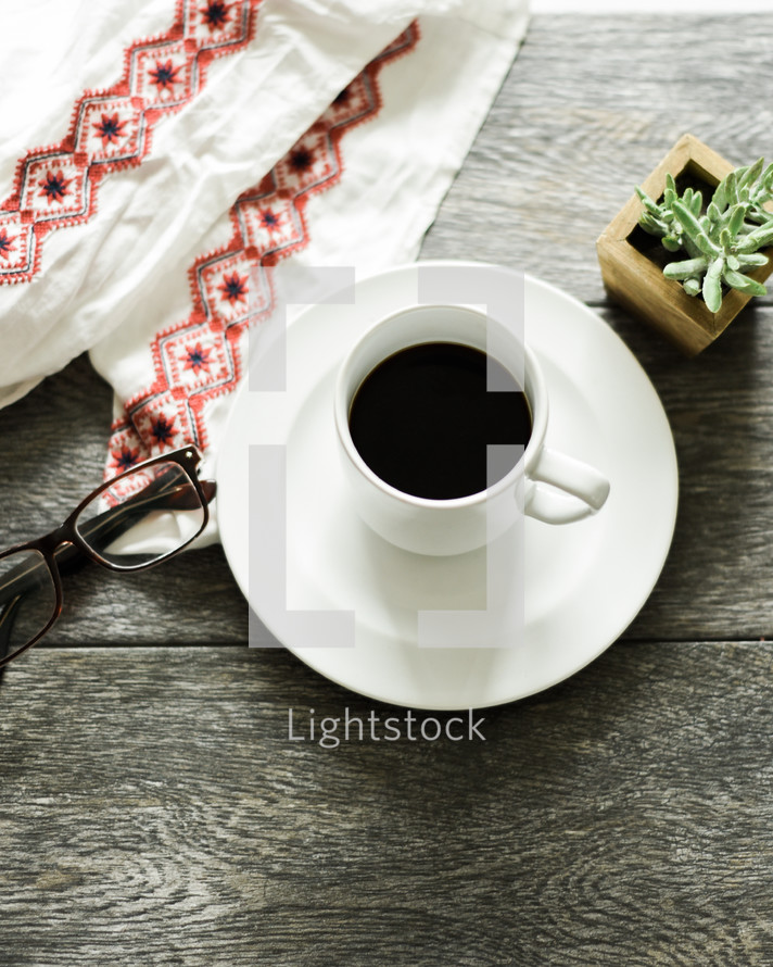 cloth napkin, reading glasses, coffee cup, saucer, house plant 