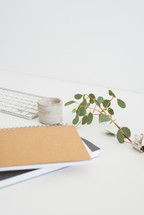stack of journal, journal, eucalyptus twig, pencil, clips, computer keyboard, gift tag, coffee cup 