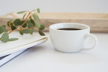 eucalyptus twig, journal, and coffee cup 