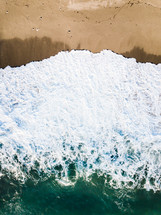 aerial view over a tide washing onto a beach 