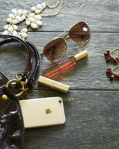 contents of a woman's purse, perfume, sunglasses, lipstick, iPhone, necklace, jewelry, earrings